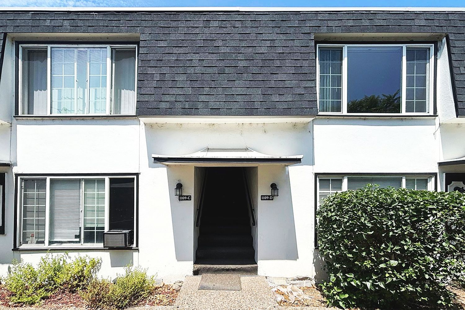 Courtyard apartment building with white stucco and a dark mansard roof